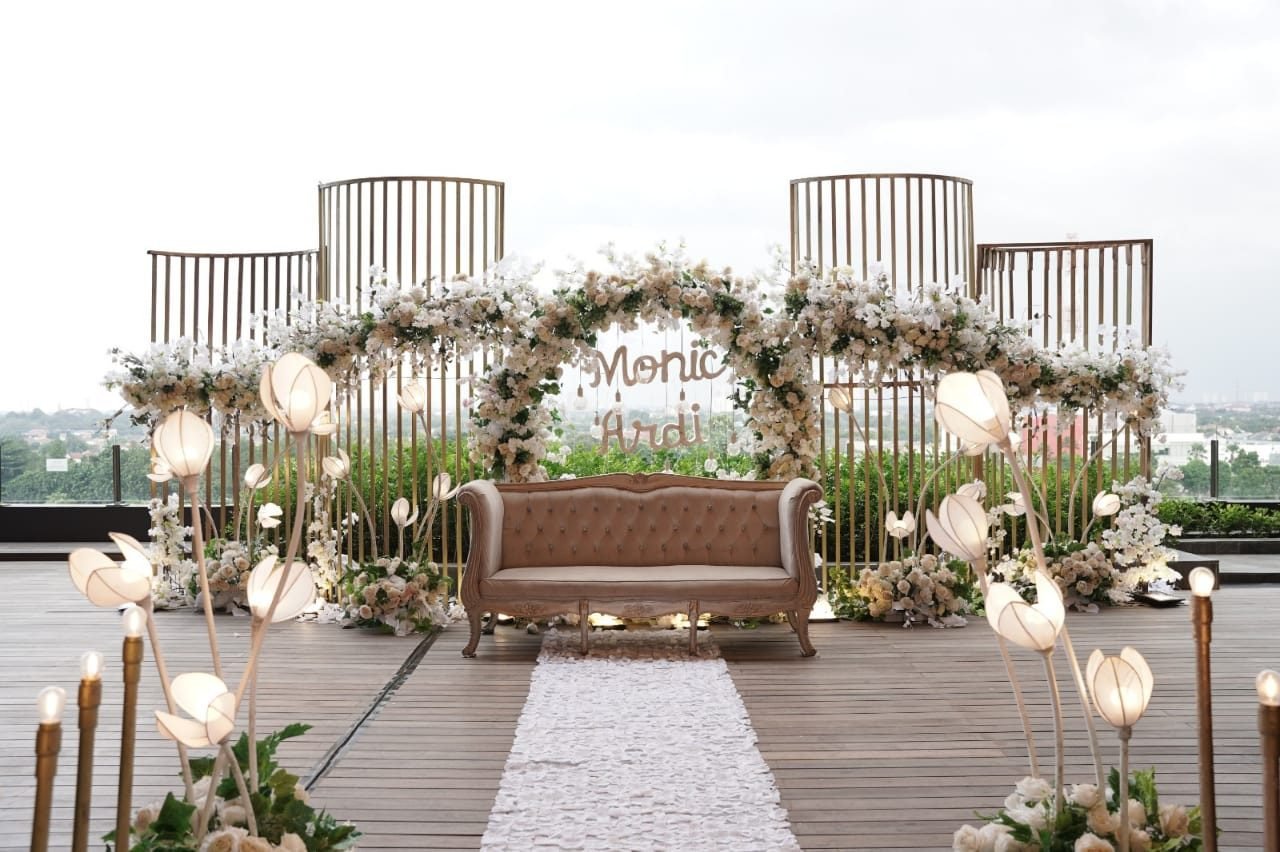 Rooftop ceremony with gold cage arch and white florals at dusk