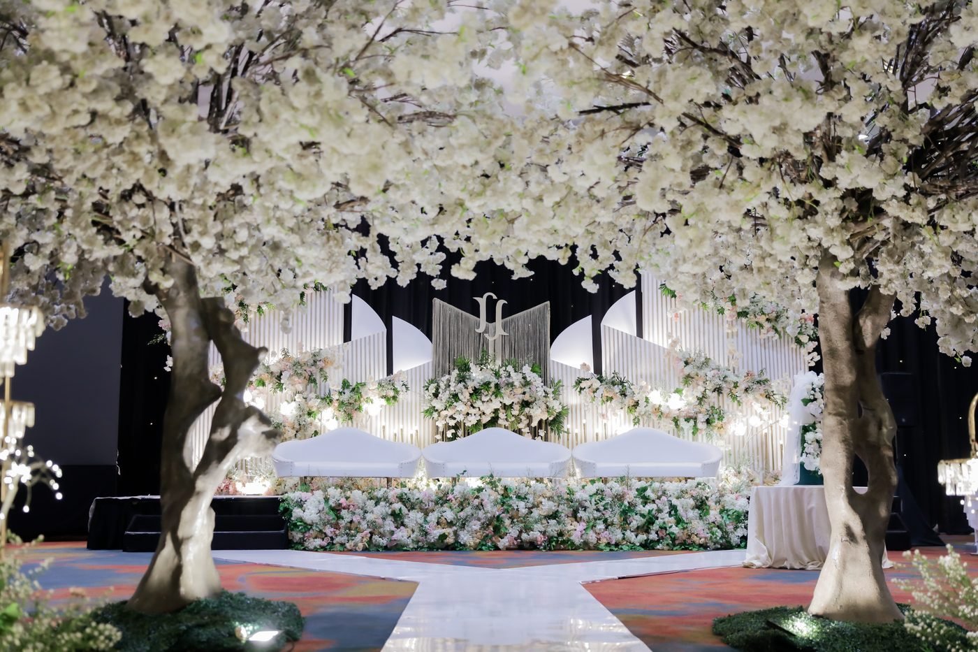 Fan-panel stage backdrop with cherry blossom trees framing the aisle