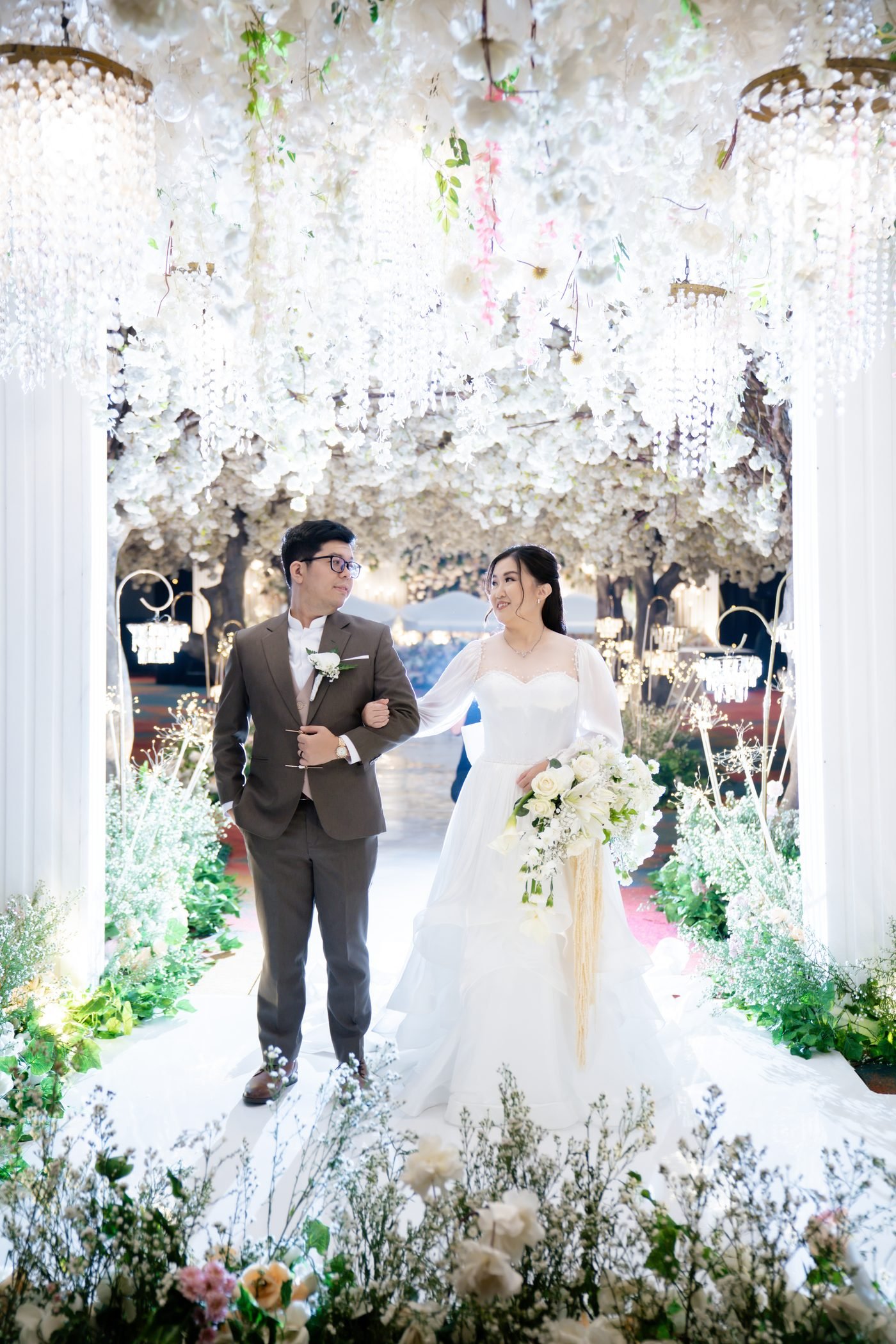 Bride and groom portrait beneath a white floral pergola